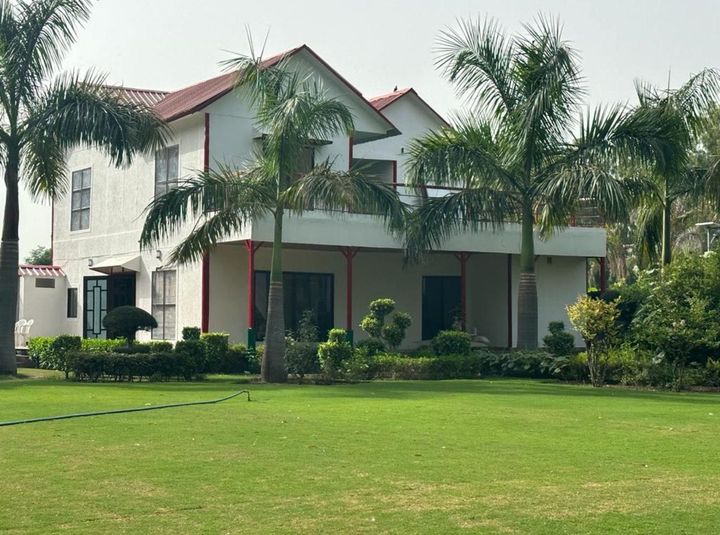 Beautiful weekend farmhouse near Noida with landscaped garden, outdoor seating area, and peaceful green surroundings