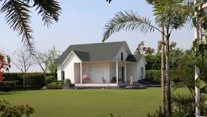 Farmhouse for sale in Noida with landscaped lawn, private driveway, and modern countryside architecture